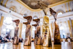Złote statuetki–nagrody w konkursie Człowiek bez Barier na tle zabytkowego wnętrza sali w Zamku Królewskim.